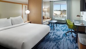 A hotel room with a large bed, a desk with a chair, a small table, a lamp, and a TV. - Fairfield Inn & Suites by Marriott Decatur (Decatur)