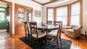 Un comedor con una mesa redonda, sillas de madera y un sillón estampado.