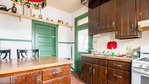 Una cocina con armarios de madera, una puerta verde, una estufa blanca y una mesa de comedor con sillas.