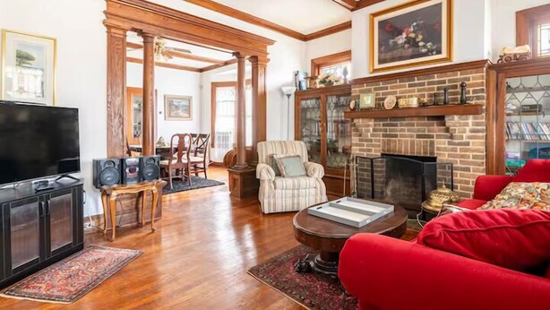 Una sala de estar con chimenea, vigas de madera, televisor y sofá rojo.