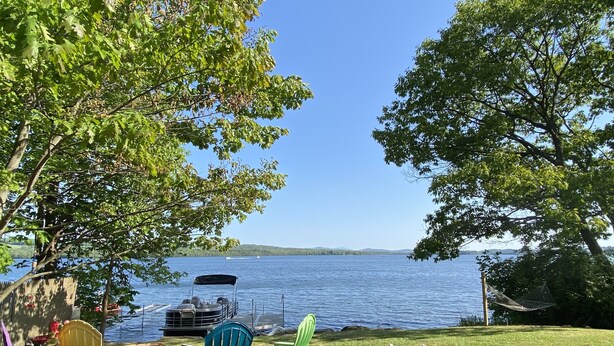 A lakeside patio with Adirondack chairs, a grill, and a view of the lake. - Charming Lakehouse private yard, boat dock/wifi. (Frankling Vermont)
