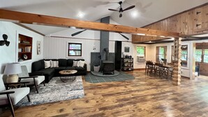 A spacious living room with a fireplace, wooden floors, and a dining area with a table and chairs. - Charming Lakehouse private yard, boat dock/wifi. (Frankling Vermont)