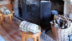 A stone fireplace with a wooden mantel, a television, and a basket of firewood.