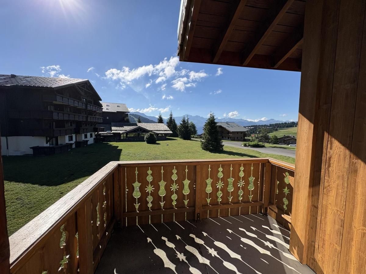 A wooden balcony with a view of a building and mountains.