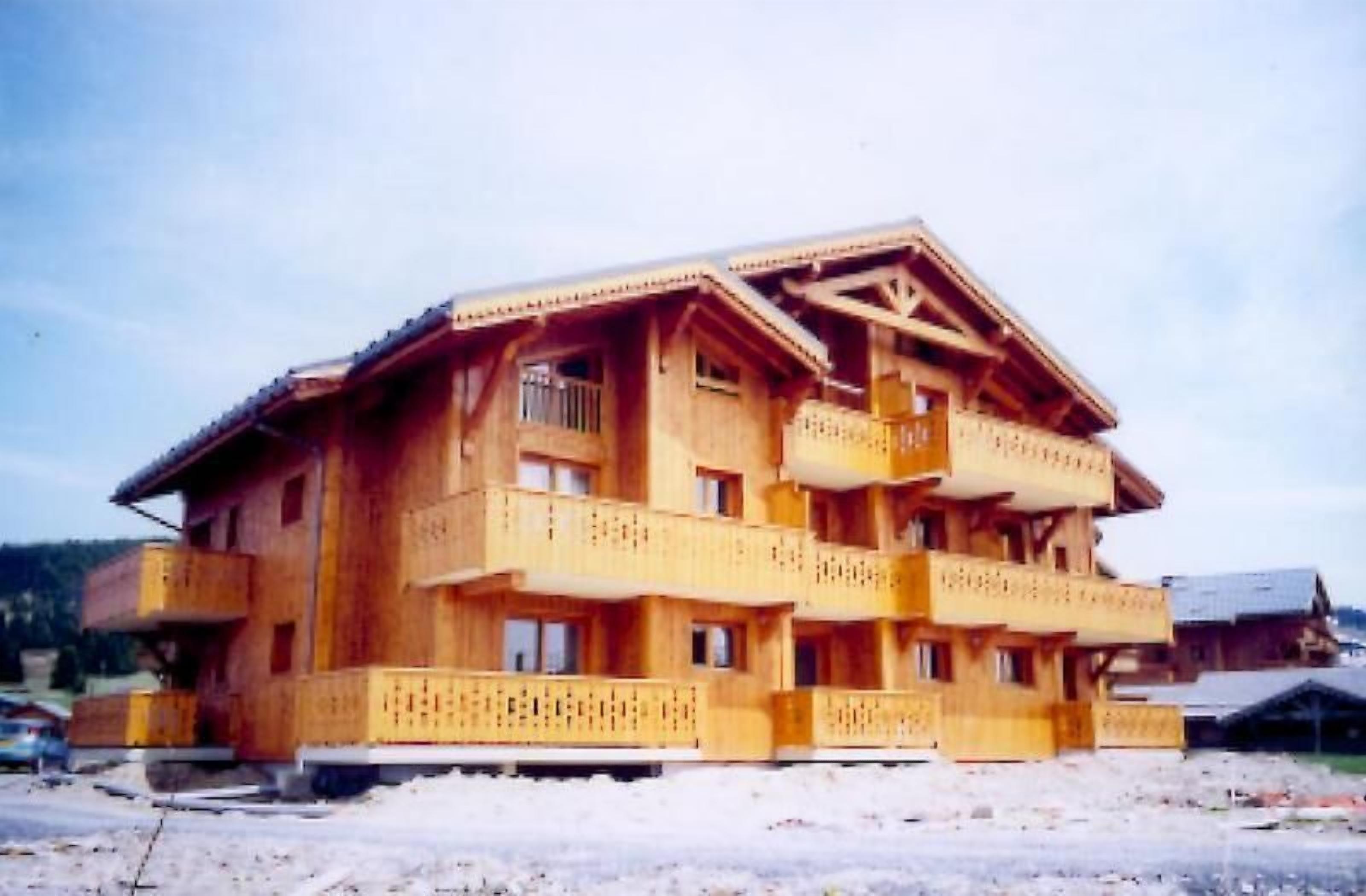 A multi-story wooden building with balconies and large windows.