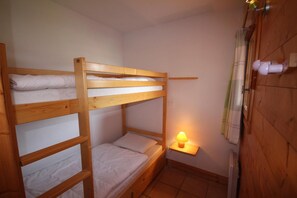 A bunk bed room with a bedside table and a lamp.