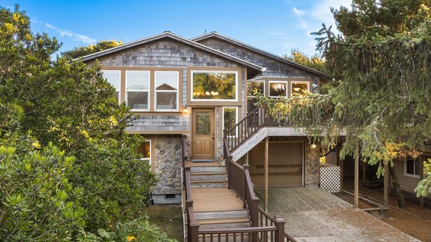 A two-story house with a stone facade, a wooden deck, and a garage.