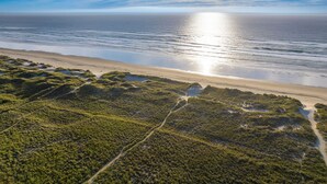 An aerial view of a beach with a clear sky and ocean.