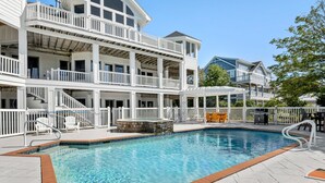 A multi-story hotel with a swimming pool, outdoor seating, and a covered patio area. - Wellfleet: Soundfront | Pool and Hot Tub | Dogs OK (Corolla)