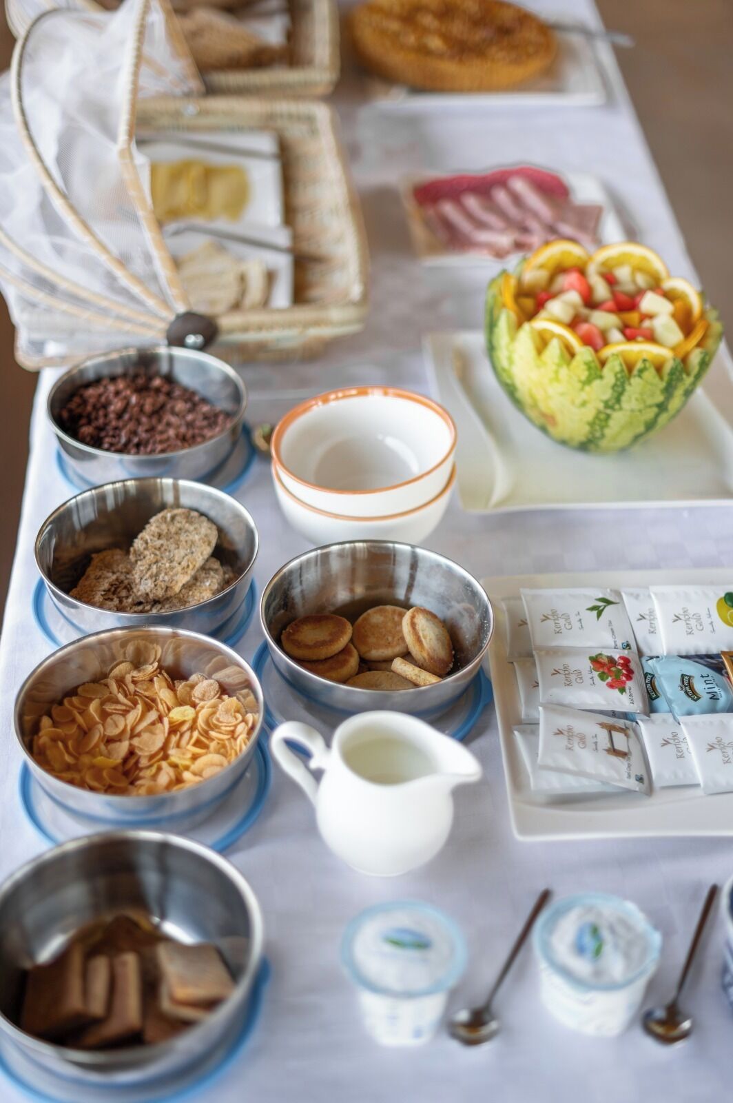 A table with various food items including bowls of nuts, cookies, and a watermelon bowl.