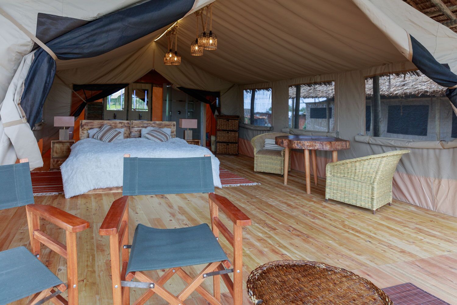 Alojamiento con carpa, una cama, muebles de mimbre y una zona de comedor.