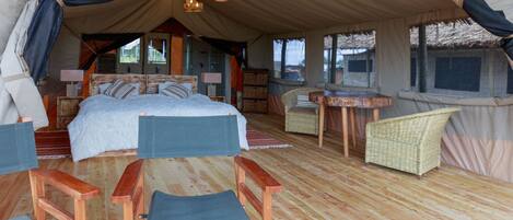 Alojamiento con carpa, una cama, muebles de mimbre y una zona de comedor.