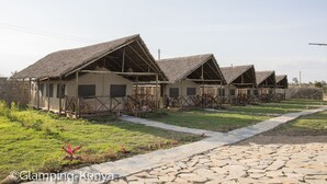 Une rangée de huttes aux toits de chaume, avec un sentier pavé de pierres qui y mène.
