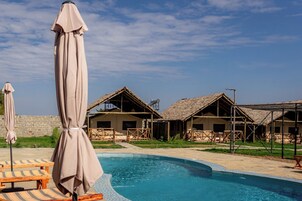 Una piscina al aire libre, sombrillas, sillones reclinables de piscina