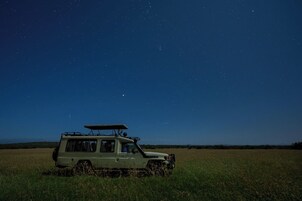 Un vehículo safari estacionado en un campo bajo un cielo estrellado.