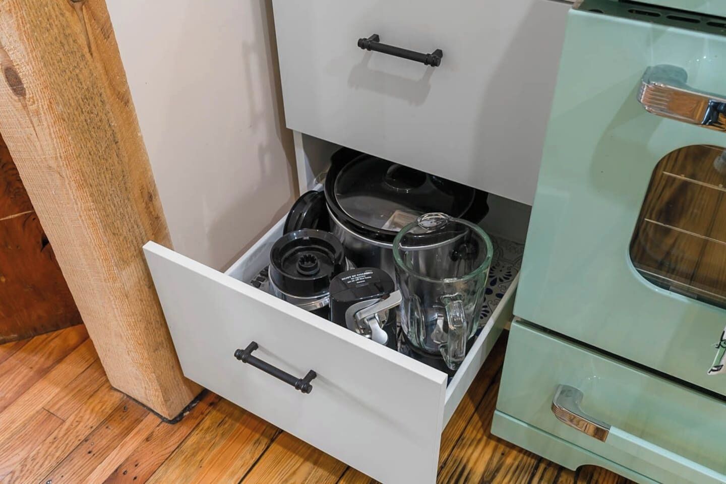 Een keuken met een lade vol keukenapparatuur en een fornuis in vintage stijl.
