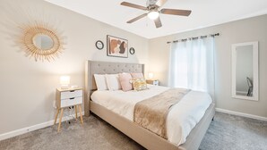 A bedroom with a bed, bedside tables, a ceiling fan, a wall-mounted mirror, and a sunburst decoration. - ★ Lux Modern Retreat ★ Downtown ★ King Beds ★ (Durham)
