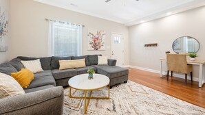 A living room with a gray sectional sofa, a round coffee table, and a desk with a chair. - ★ Lux Modern Retreat ★ Downtown ★ King Beds ★ (Durham)