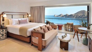 Une chambre d’hôtel dotée d’un grand lit, d’un canapé, d’un coin repas et offrant une vue sur la mer.