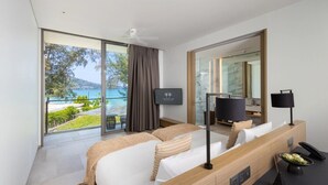 Une chambre d’hôtel moderne dotée d’un grand lit, d’une télévision, d’un bureau avec un téléphone et offrant une vue sur la mer.