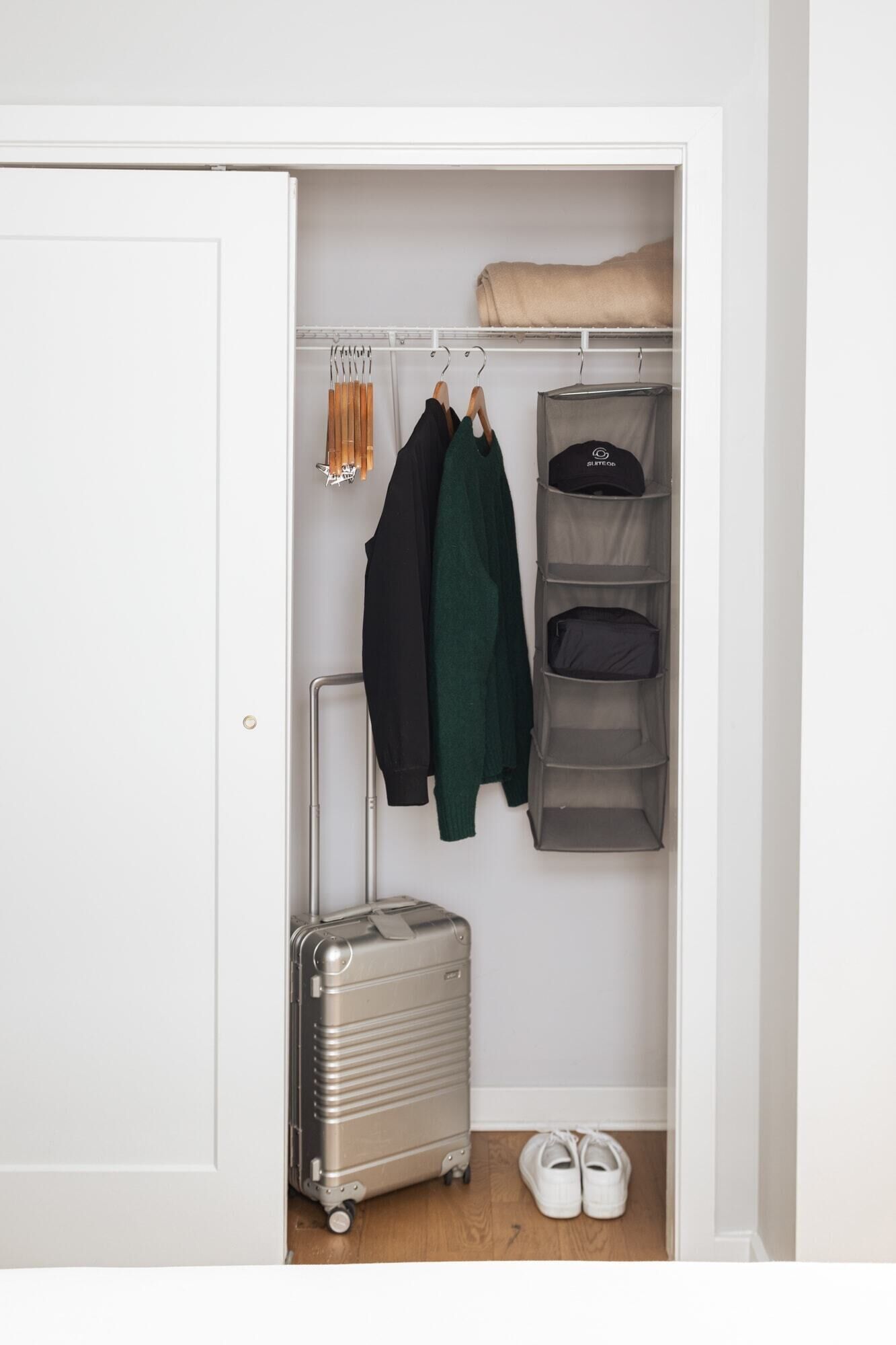Ein Schrank mit Kleidern, einem Koffer und einem Schuhpaar.