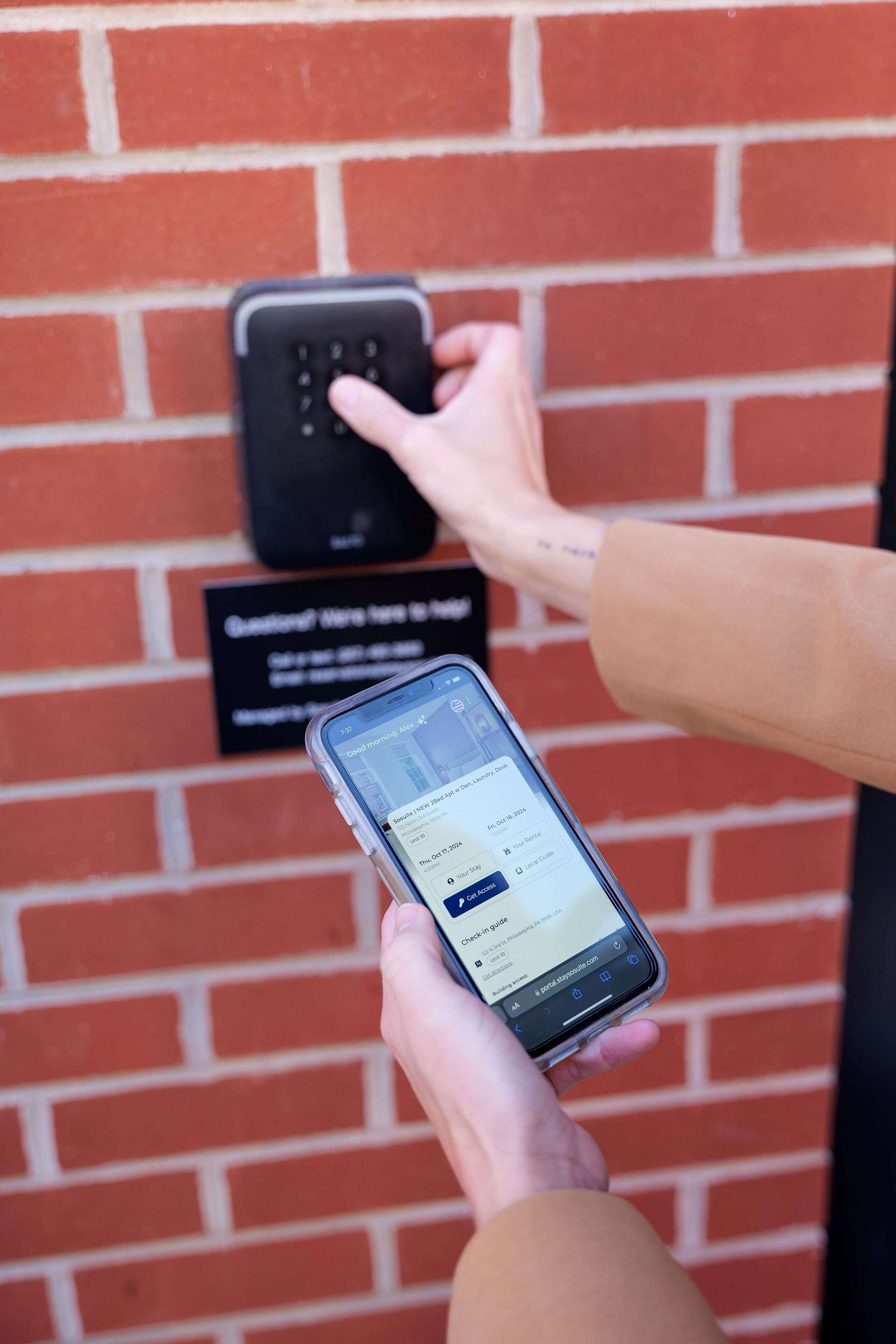 A person using a smartphone to interact with a keypad, possibly for a hotel or service access.