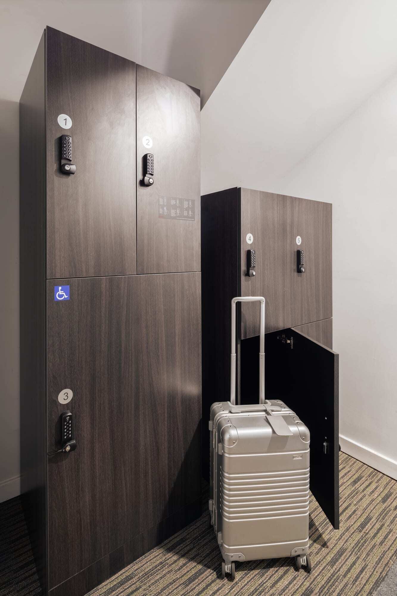 A hotel room with a large wardrobe, a suitcase, and a wheelchair-accessible sign.