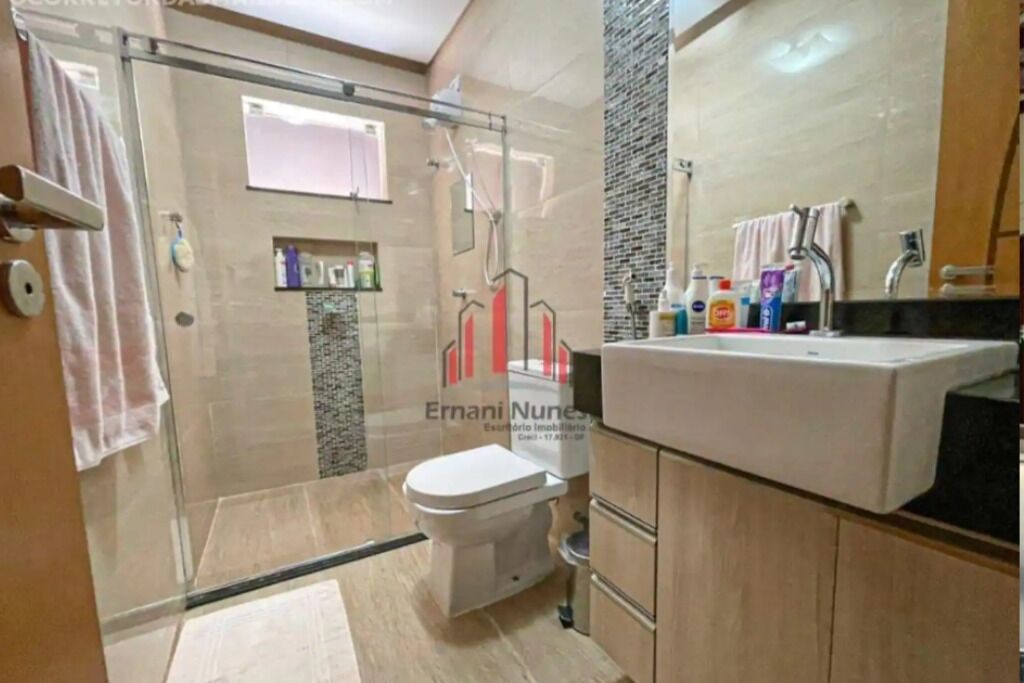 A modern bathroom with a glass shower enclosure, a toilet, and a vanity with a mirror.