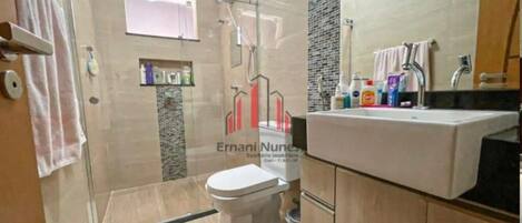 A modern bathroom with a glass shower enclosure, a toilet, and a vanity with a mirror.