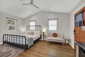 A bedroom with a bed, a nightstand, a chair, and a small table.