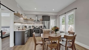 A modern kitchen with a central island, built-in appliances, and a dining area with wooden chairs. - The Grove Estate 8BD/7BA!  Perfect For Groups! (Fredericksburg)