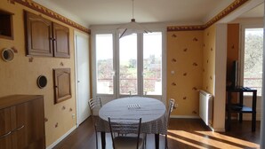 Un coin repas avec une table ronde et des chaises, un buffet en bois et un téléviseur posé sur un meuble.
