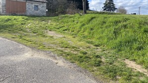 Un chemin de gravier mène à un bâtiment en pierre doté d’une porte en bois.