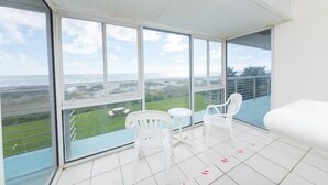 A balcony with a view of the sea, white chairs, and a small table. - 2nd floor beach condo (Cocoa Beach)