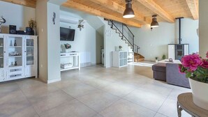Ein großzügiger Wohnbereich mit Holzboden, einer Treppe, einem Kamin und einem an der Wand befestigten Fernseher.
