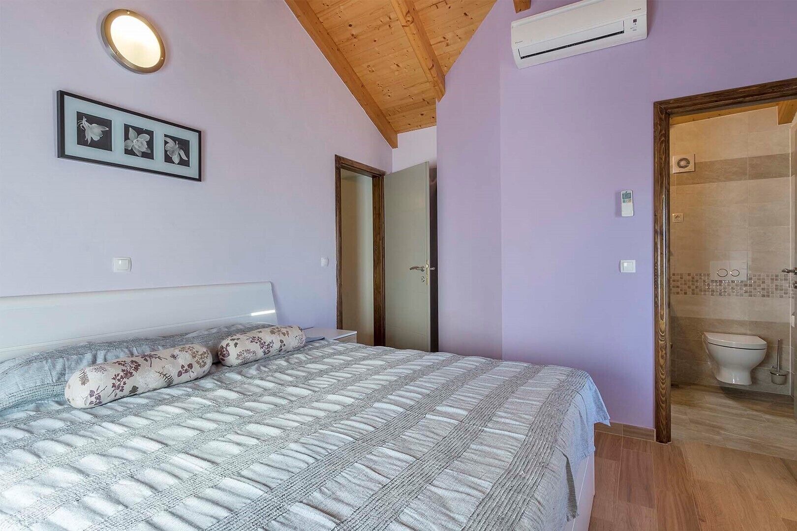 Une chambre à coucher avec un lit, une porte et une salle de bain visible à travers une porte ouverte.