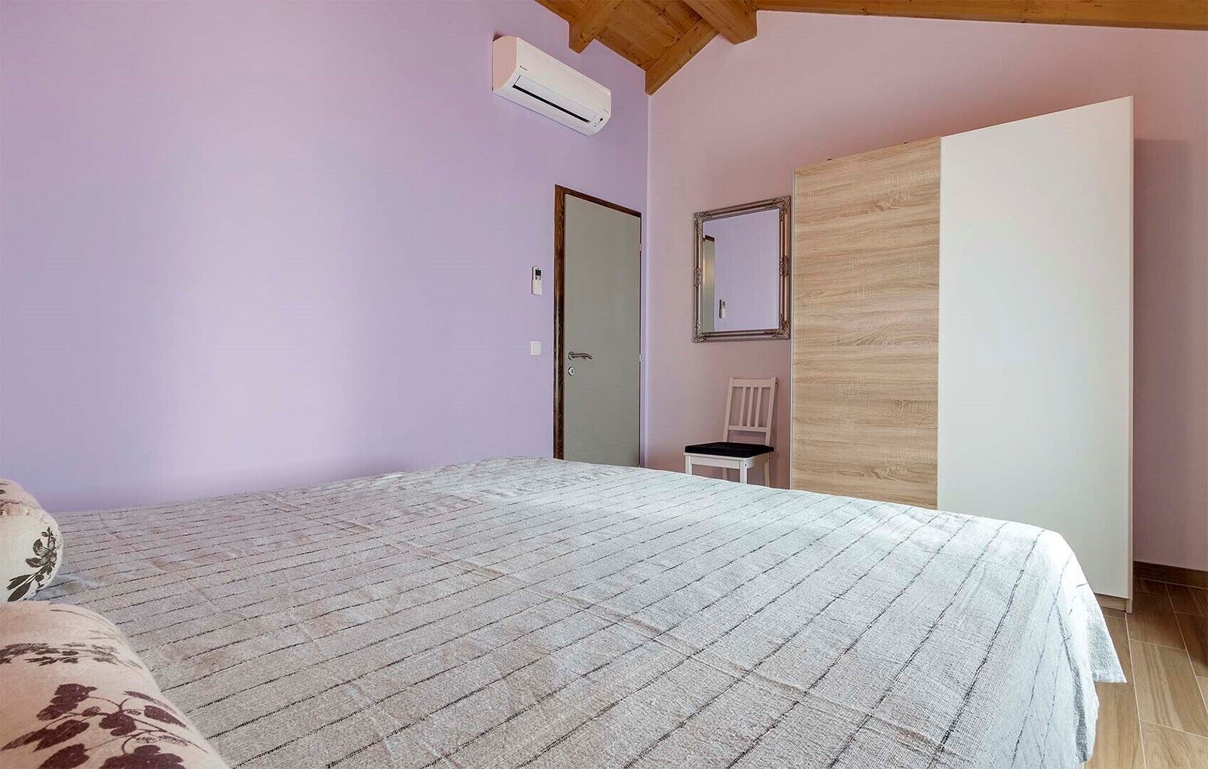 Ein Schlafzimmer mit Bett, Stuhl, Kleiderschrank und Klimaanlage.