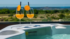 Two glasses of orange juice on a spa tub with a scenic view.