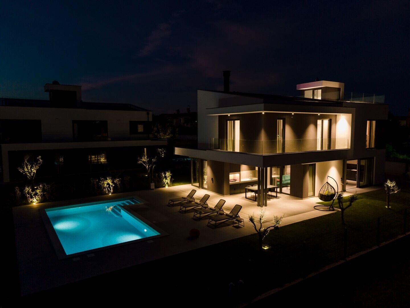 A modern two-story house with a swimming pool and outdoor seating area.