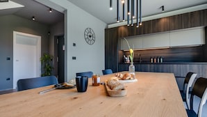 A modern dining area with a wooden table, chairs, and a clock on the wall.