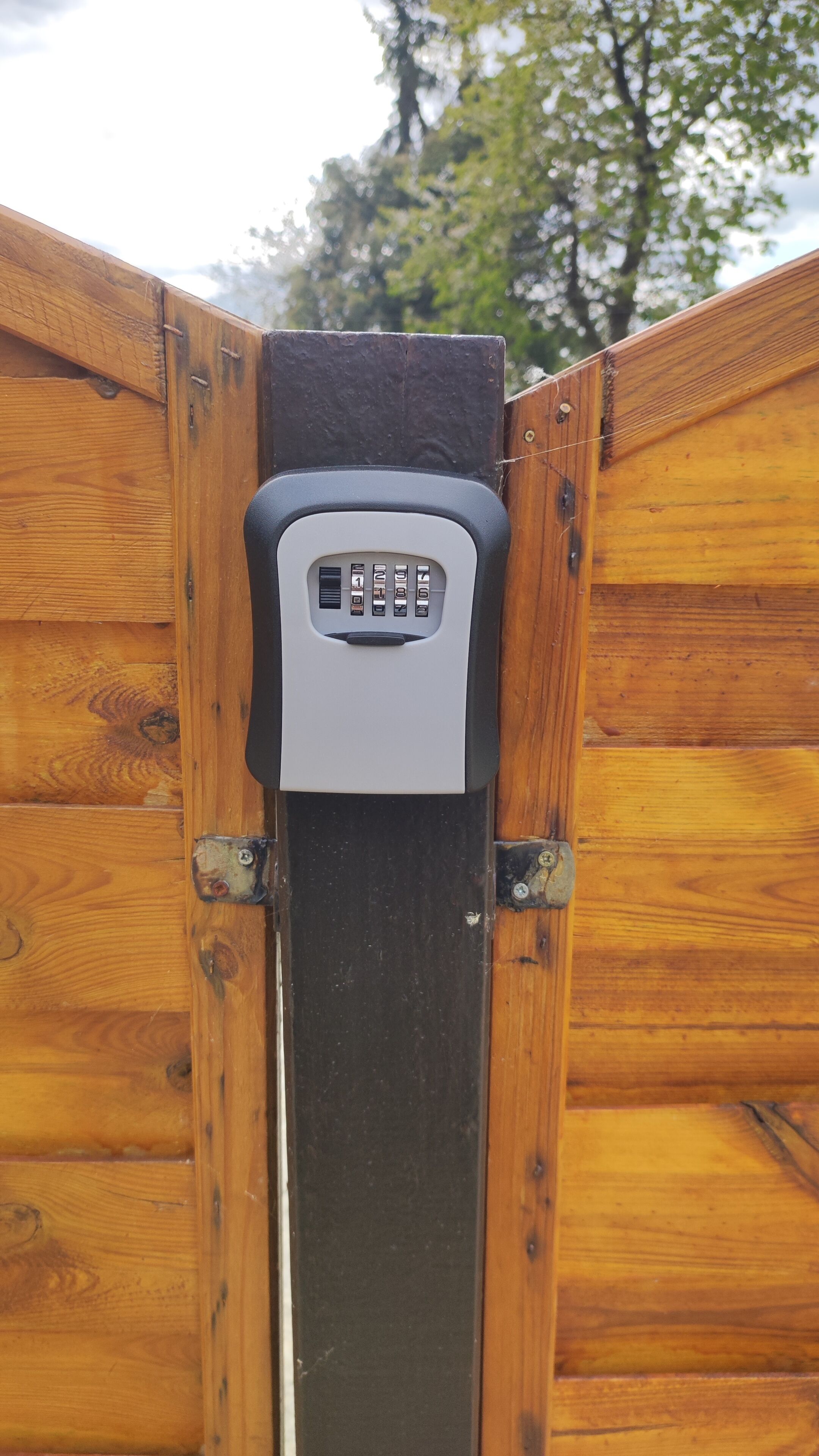 Een houten poort met een keypadslot.