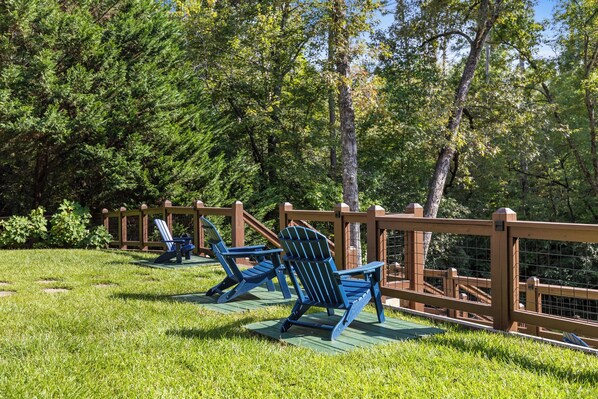 A deck with blue Adirondack chairs and a wooden railing.