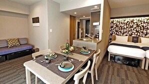 A hotel room with a dining area, a sofa, a bed, and a bathroom. - MONday Apart Premium Hamamatsucho (Tokyo)