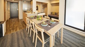 A modern hotel room with a dining area, kitchenette, and a large window. - MONday Apart Premium Hamamatsucho (Tokyo)