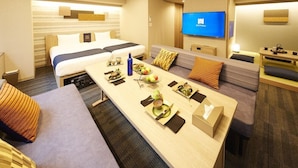 A hotel room with a bed, a sofa, a dining table with food and drinks, a TV, and a desk with a chair. - MONday Apart Premium Hamamatsucho (Tokyo)