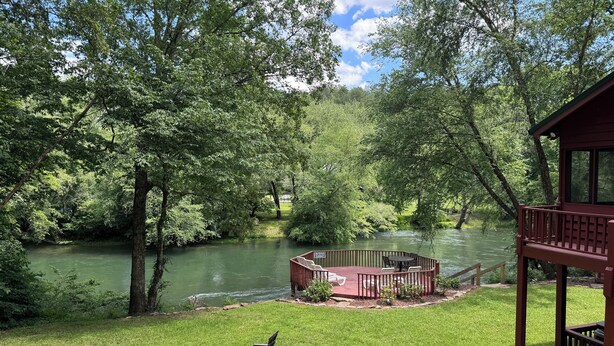 A riverside deck with outdoor seating and a hot tub. - Bigfoot's River Retreat (Mineral Bluff)