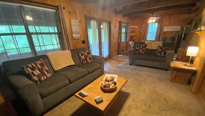 A cozy living room with a grey sofa, a wooden coffee table with decorative items, and a grey couch in the background. - Bigfoot's River Retreat (Mineral Bluff)