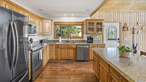Une cuisine moderne avec des meubles en bois, des appareils en acier inoxydable et un plan de travail en granit.