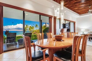 A dining area with a large table, chairs, and a view of the ocean. - Makena Surf, #c-103 2 Bedroom Condo by RedAwning (Kihei)