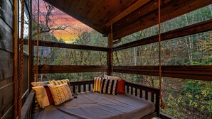 A wooden cabin with a bed facing a forest view. - Best Family Cabin - Indoor Pool, Cinema, Arcade, Putt Putt, Spa, Fire Pit, Creek (Sevierville)